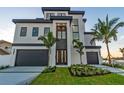 Elegant modern home with a two-car garage, lush landscaping, and a grand entrance at 2832 W Vina Del Mar Blvd, St Pete Beach, FL 33706