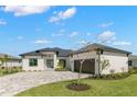 White one-story house with dark gray metal roof, paver driveway, and landscaping at 1810 4Th E St, Palmetto, FL 34221