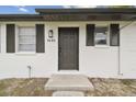 Newly renovated house exterior boasts a modern look with a gray door and white walls at 9480 Midway St, Spring Hill, FL 34608