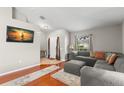 Bright living room with hardwood floors, gray sectional sofa, and large TV at 30735 Lanesborough Cir, Wesley Chapel, FL 33543