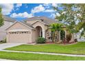 Tan two-story house with a two-car garage and lush landscaping at 30552 Latourette Dr, Wesley Chapel, FL 33545