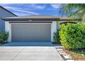 Two-car garage with gray door and well-maintained landscaping at 12110 Miracle Mile Dr, Riverview, FL 33578