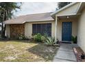 House exterior featuring a dark blue front door, stone accents, and well-maintained landscaping at 7140 Orchid Lake Rd, New Port Richey, FL 34653