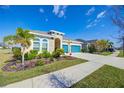 Attractive single-story home with a blue garage door, lush landscaping, and a well-maintained lawn at 5502 Limelight Dr, Apollo Beach, FL 33572
