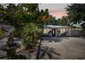 Charming home featuring tropical landscaping, white exterior, a metal roof and spacious driveway at 1906 2Nd St, Indian Rocks Beach, FL 33785