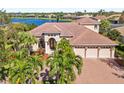 This waterfront home has a red tile roof, a brick driveway, and mature palm trees at 7925 Royal Queensland Way, Lakewood Ranch, FL 34202
