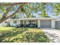 Single-story home with a tree-filled front yard and a tire swing at 5410 Palm Drive, New Port Richey, FL 34652