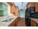 Spacious kitchen featuring granite counters, stainless steel sink, black refrigerator, and wood cabinets at 2342 Hazelwood Ln, Clearwater, FL 33763
