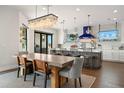 Bright dining area with a long table, stylish chairs, and a modern chandelier adjacent to an open concept kitchen at 7949 2Nd S Ave, St Petersburg, FL 33707