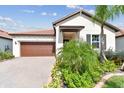 House exterior featuring a two-car garage and manicured landscaping at 5512 Little Path Dr, Wimauma, FL 33598