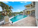 Beautiful pool and hot tub with travertine tile, tropical plants, and elegant architecture on display at 3341 Gulf Blvd, Belleair Beach, FL 33786