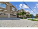 Tan three-story townhouses with two-car garages, paver driveways, and lush landscaping at 348 Larboard Way, Clearwater, FL 33767