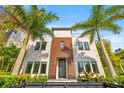 Modern home with wood and white facade, palm trees, manicured landscaping, and black fence at 103 5Th N Ave, St Petersburg, FL 33701