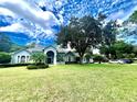 Charming single-story home with a well-manicured lawn and lush landscaping under a blue sky at 168 Rue Des Chateaux, Tarpon Springs, FL 34688