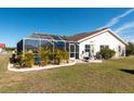 A backyard with a screened-in pool, patio, and lush green landscaping at 701 Westmont Way, Sun City Center, FL 33573