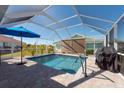Screened-in pool area with a blue umbrella, patio, and lush green landscaping at 701 Westmont Way, Sun City Center, FL 33573