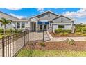 Single-story home with a gray exterior, a paved walkway, and a black fence at 10741 Tippecanoe Pl, Parrish, FL 34219