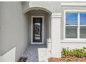 Home's entryway shows a dark door framed by an elegant arch, complemented by lush landscaping at 6681 Michael Favor Way, Wesley Chapel, FL 33545