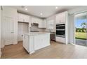 Modern white kitchen featuring stainless steel appliances, an island and natural light at 6681 Michael Favor Way, Wesley Chapel, FL 33545