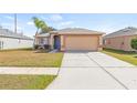 Tan house with a blue door, two-car garage, and a grassy yard at 6340 Sushi Ct, Wesley Chapel, FL 33545