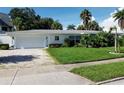A white single-story house with a gravel driveway, lush lawn, and mature landscaping at 15301 Harbor Dr, Madeira Beach, FL 33708