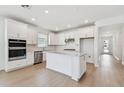 Bright kitchen boasts white cabinets, stainless steel appliances, and an island with a stone countertop at 6741 Michael Favor Way, Wesley Chapel, FL 33545