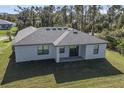 Aerial view of a single-story home with a gray roof, lawn, and sliding glass doors to the patio at 5321 Crestline Ter, Port Charlotte, FL 33981