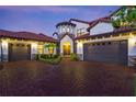 Two-story house with a brick driveway and three-car garage at dusk at 8414 Dunham Station Dr, Tampa, FL 33647