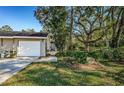 Tan house with white garage door and walkway, surrounded by lush landscaping at 4399 Brooker Creek Dr, Palm Harbor, FL 34685