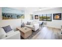 Living room with white sofas, wood floors, and coastal artwork at 1515 Pinellas Bayway S # B28, Tierra Verde, FL 33715