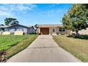 Front view of a single-story house with a brown garage door and a landscaped yard at 10801 Fillmore Ave, Port Richey, FL 34668