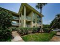 Condo building's exterior featuring balconies, green lawn, mature trees, and a clear blue sky at 2690 Coral Landings Blvd # 722, Palm Harbor, FL 34684