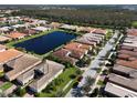 An aerial view of a residential community featuring lush green lawns, a serene lake, and beautiful tile roofs at 4847 Marble Springs Cir, Wimauma, FL 33598