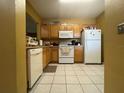 Kitchen with wood cabinets, white appliances, and tile flooring at 6007 Skydale Way # 201, Riverview, FL 33578