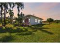 Ranch-style home with a large yard and palm trees at sunset at 1810 Curry Rd, Lutz, FL 33549