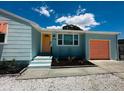 Updated home exterior featuring a teal facade and orange garage at 2658 48Th S St, Gulfport, FL 33711