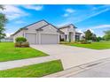 Two-story house with three-car garage, manicured lawn, and mature trees at 913 Buckhurst Dr, Spring Hill, FL 34609