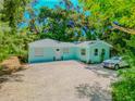 Charming light blue house with a gravel driveway, surrounded by lush greenery at 2562B Ashton Rd, Sarasota, FL 34231