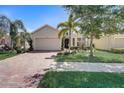 Tan house with brick driveway, palm trees, and manicured landscaping at 1804 Pacific Dunes Dr, Sun City Center, FL 33573