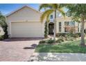 Tan house with brick driveway, palm trees, and manicured landscaping at 1804 Pacific Dunes Dr, Sun City Center, FL 33573