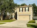 Tan two-story house with two-car garage and landscaping at 2706 Mingo Dr, Land O Lakes, FL 34638