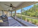 Enclosed patio featuring two ceiling fans, three wicker chairs, and views of the green backyard at 2104 Hembury Pl # 33, Sun City Center, FL 33573