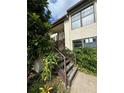 Close up exterior of the home with a wooden staircase, stucco exterior, and vibrant plants at 2571 Cyprus Dr # 1-202, Palm Harbor, FL 34684