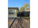 Side yard features space for parking or storage with a wooden fence and some greenery at 3718 E Henry Ave, Tampa, FL 33610