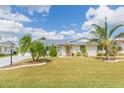 Beautiful home with a lush green lawn, palm trees, and well-maintained landscaping, creating a welcoming curb appeal at 907 La Jolla Ave, Sun City Center, FL 33573
