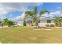 Well-maintained lawn with palm trees accenting a charming home with white accents and a lovely garden at 907 La Jolla Ave, Sun City Center, FL 33573