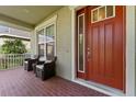 Front porch with red door and wicker chairs at 9157 Bella Vita Cir, Land O Lakes, FL 34637