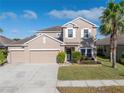 Two-story house with beige exterior, three-car garage, and manicured landscaping at 11339 Tayport Loop, New Port Richey, FL 34654