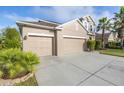 Beige two-story house with three-car garage and lush landscaping at 11339 Tayport Loop, New Port Richey, FL 34654