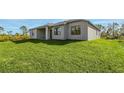 View of the rear of the home with covered patio and large grassy yard at 5227 Dayton Ln, Port Charlotte, FL 33981